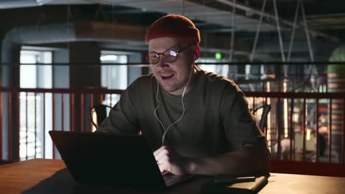 Man Video Conferencing on Laptop in Modern Office