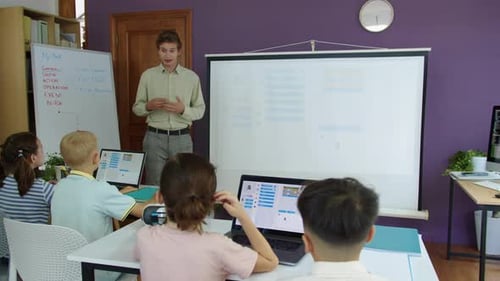 Junger Lehrer hat Programmierunterricht mit einer Gruppe von Kindern