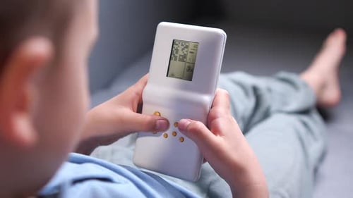 Back View Closeup of a Boy Playing Old Handheld Console Video Game