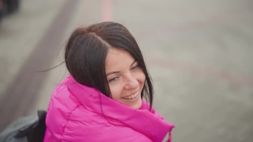 Smiling woman in pink jacket looking back