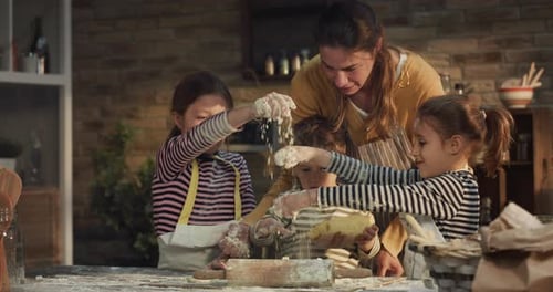 Cinematic authentic shot of happy mother and her little kids are having fun to make dough with flo