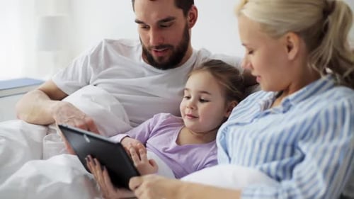 Happy family using tablet in bed together