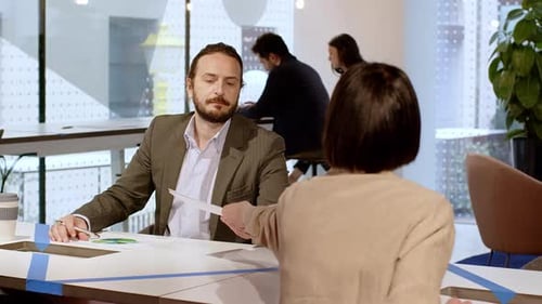 Businesswoman handing colleague documents in office