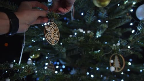 Decorating a Christmas Tree at Night with Ornaments