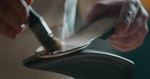 Close up of a shoemaker glueing the leather on the shoes in a shoe factory. Concept: handmade, fas
