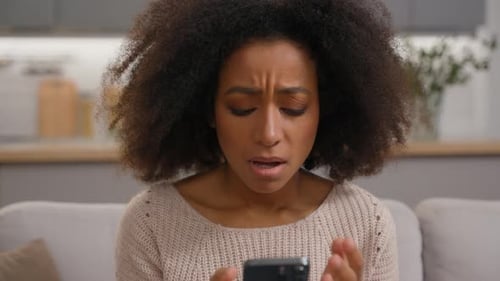 Frustrated Woman Looking at Her Phone Indoors