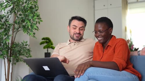 Couple Relaxing on Sofa Looking at Laptop