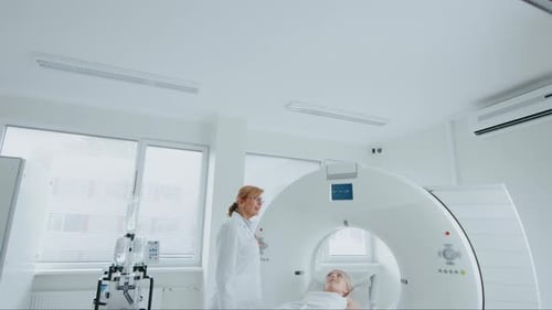 In Medical Laboratory Female Radiologist Controls MRI or CT Scan with Female Patient Undergoing Pro