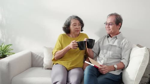 Happiness senior couple sitting on sofa cheer coffee cup and drinking in living room.