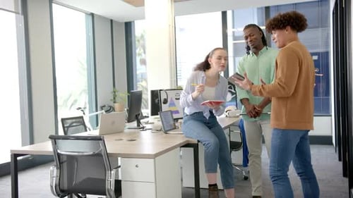 Collaborating on project ideas, colleagues using tablet and notepad in modern office