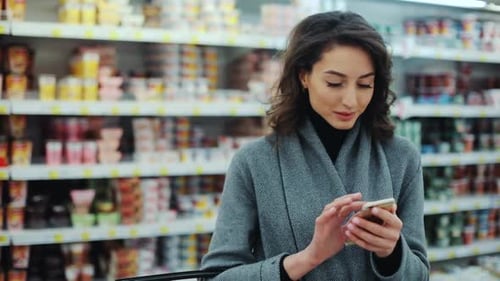 Young Woman Stand Use Phone in Supermarket Smiling Beautiful Shopping Internet Buying Technology