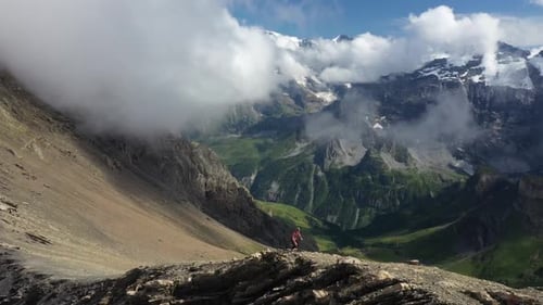 Aerial shot of a young and athletic man running the last part up the ridge to the top of the cliff,