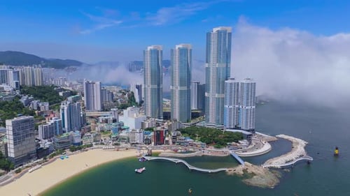 Aerial View of Modern Skyscrapers a Sandy Beach and a Curving Pedestrian Bridge Along the Ocean