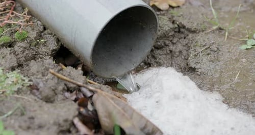 Water Flowing from Pipe onto Muddy Ground