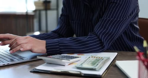 Hands Type on Laptop Counting Money at Desk