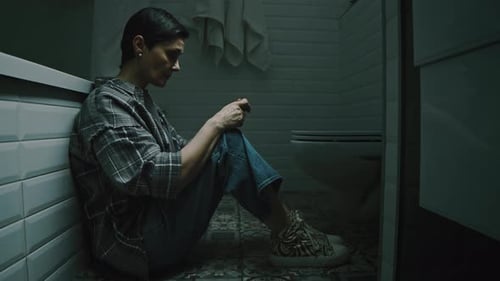 Worried Woman Sits Alone in Bathroom