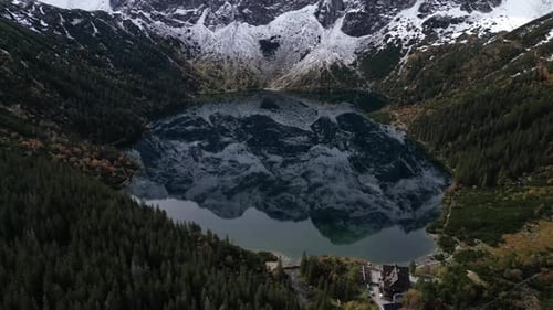 Aerial footage of snowcapped peaks reflected in Morskie Oko Lake in Zakopane Poland