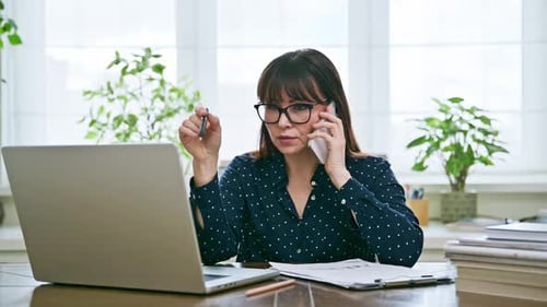 Woman Working At Desk Talking On Cell Phone