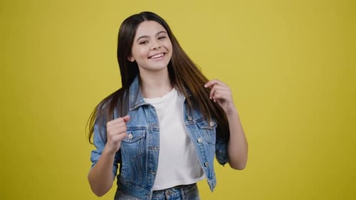 Teen Girl Dancing Happily Against Yellow Background
