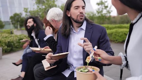 Business people eating takeaway food during lunch break meeting outside the office