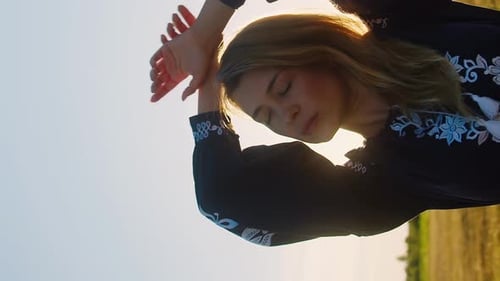 Vertical caucasian romantic woman posing on a wheat field in evening shining rays of light