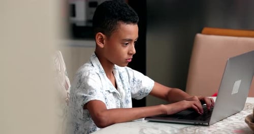 Petit garçon préadolescent utilisant un ordinateur portable à la maison pour naviguer sur Internet