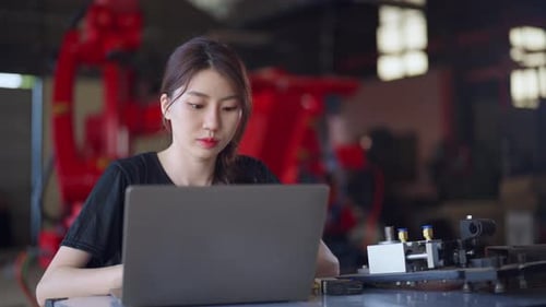 Female engineer in a black shirt works intently on her laptop