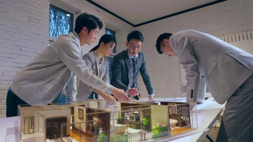 Architects reviewing blueprints and brainstorming idea about house project in modern office