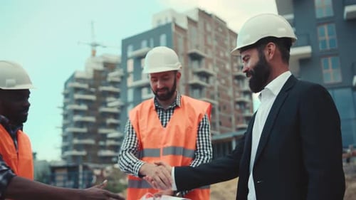 Multiracial Professional Construction Workers Having a Meeting with a Young Serious Businessman in