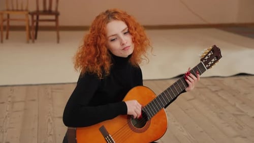 Woman Plays Guitar with Curly Red Hair