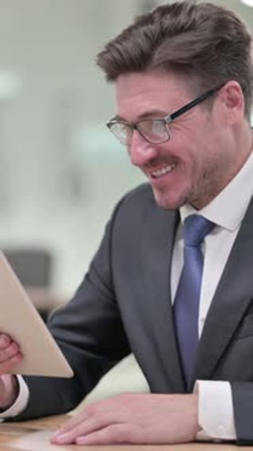 Professional Middle Aged Businessman doing Video Chat on Tablet in Office, vertical video