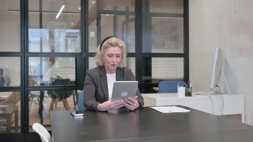 Senior Old Business Woman Doing Video Chat on Tablet in Office