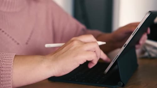 Mão de mulher irreconhecível usando um tablet gráfico com caneta Stylus em um café recortado