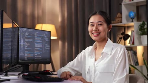 Asiatische Programmiererin lächelt in die Kamera, während sie eine Software-Ingenieurin erstellt, die eine App entwickelt