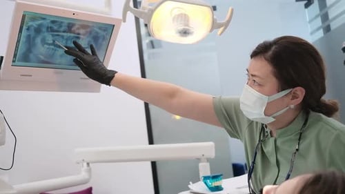 Woman Dentist and Patient Reviewing Digital Xray on Screen at Modern Clinic