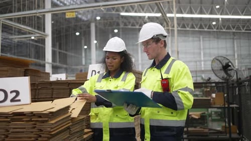 Verschiedene Fabrikarbeiter inspizieren Pappkartons im Lager