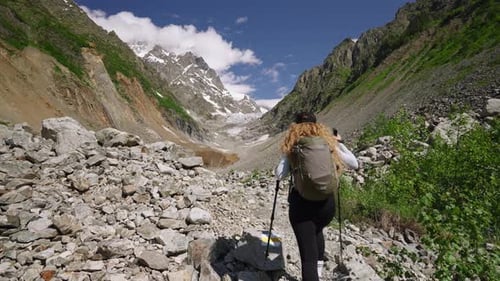 Woman Hikes in Svaneti Mountains to Chalaadi Glacier Hiker with Backpack and Poles Explores Rocky