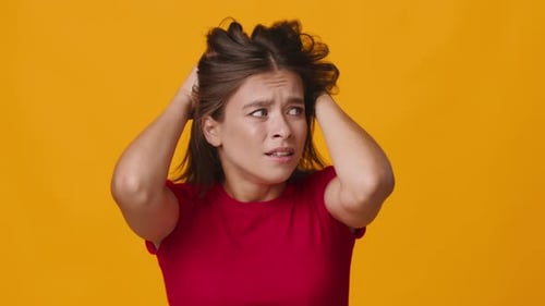 Distressed Woman Clutches Hair in Close-up Studio Shot