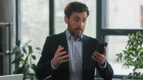 Man Cheers While Looking at Smartphone in Office