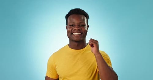 Thumbs up, man and face in studio for success, winning deal and bonus achievement on blue