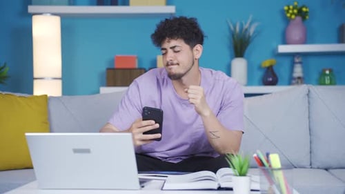 Man Using Phone and Laptop in Home Office