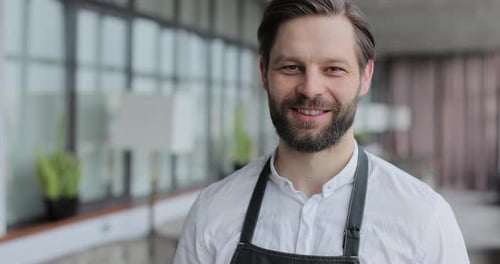 Close Up Male Restaurant Waiter in Apron Standing in Empty Cafe Hall Looking and Smiling on Camera