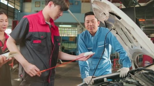 Ein männlicher Automobilbetreuer berät das Team eines Mechanikers in einer Autowerkstatt.