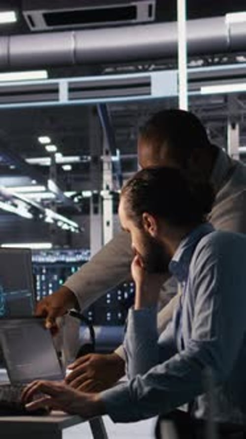 Vertical Video Data Center Engineers Use Laptop Collaborating on Doing AI Software Updates