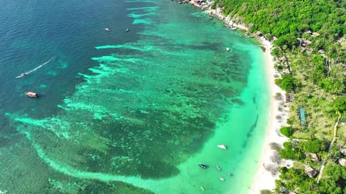 A tropical island with resorts surrounded by clear waters. Drone view.