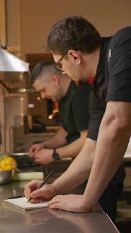 Chef Writing Notes while Planning Menu in Restaurant Kitchen