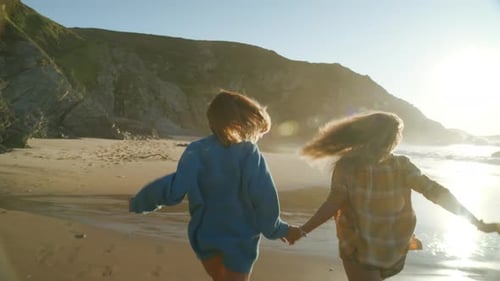 Two Friends Run Barefoot on Empty Beach