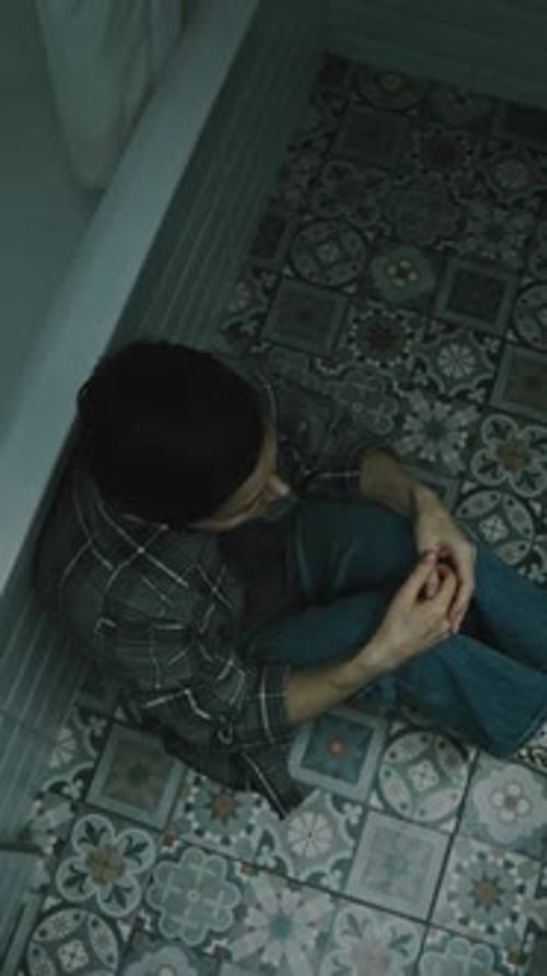 Vertical Top View of Depressed Woman Sitting on Floor in Bathroom