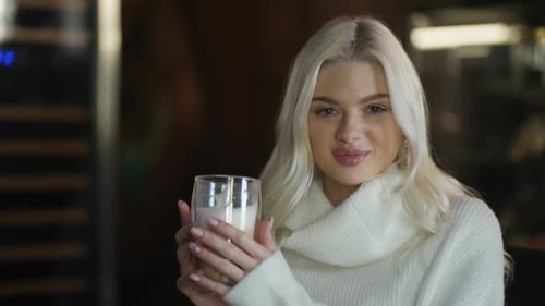 Portrait of a Young Woman Drinking Cappuccino in a Restaurant Posing for Camera