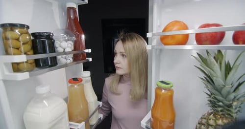 Woman Looking Into Refrigerator Full of Food